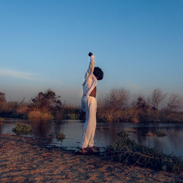 A person stretching outdoors with a serene landscape in the background.